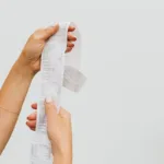 Seseorang memegang struk belanja panjang sebagai bukti transaksi pembelian